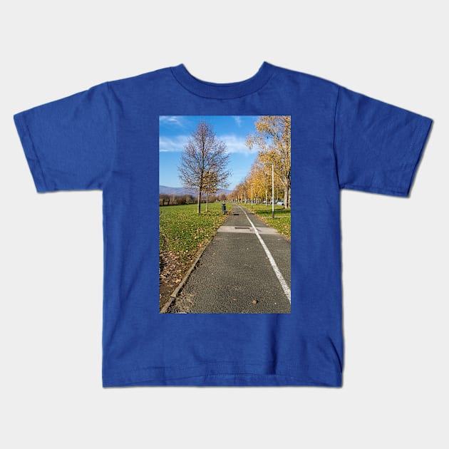 Walkway in nature with a bench, trees and street lamps Kids T-Shirt by KargacinArt